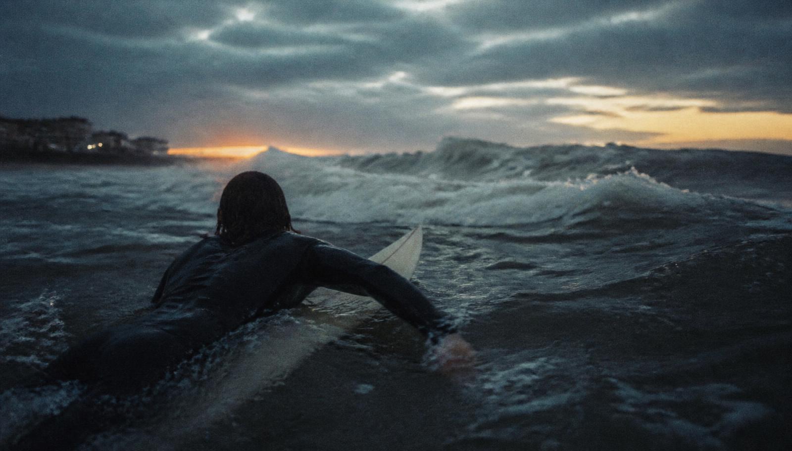 A surfer paddling out at dawn at New Smyrna Beach